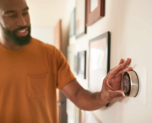 Person adjusting thermostat in home