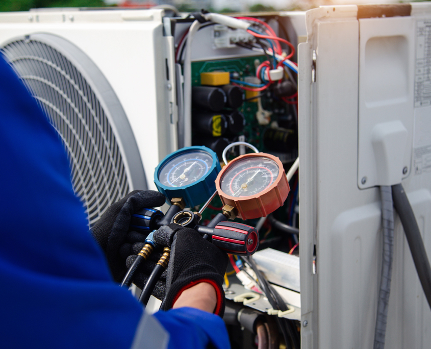 air conditioner technician is using a gauge to measure the refrigerant pressure